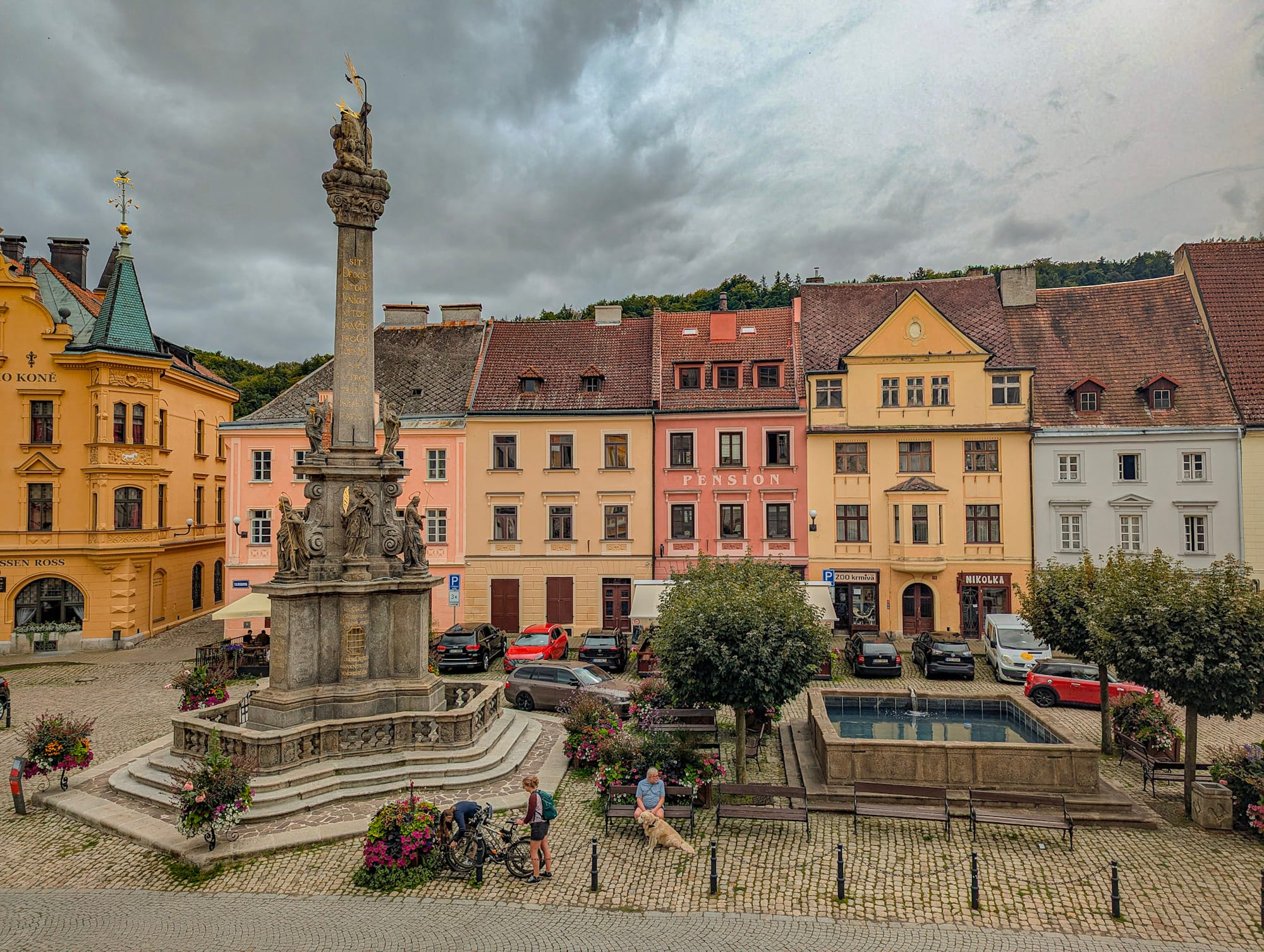 Ein Marktplatz einer tschechischen Kleinstadt mit Mariensäule, Brunnen und dahinter einer Häuserzeile.