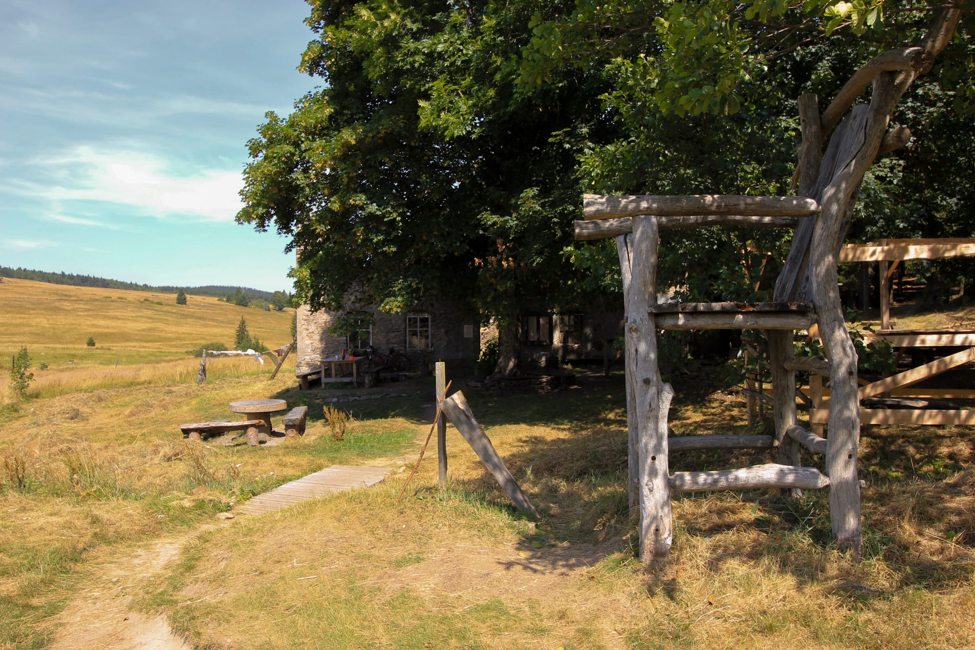 Ein Tisch mit Holzbänken und ein großer Holzstuhl vor einem Haus in Königsmühle.