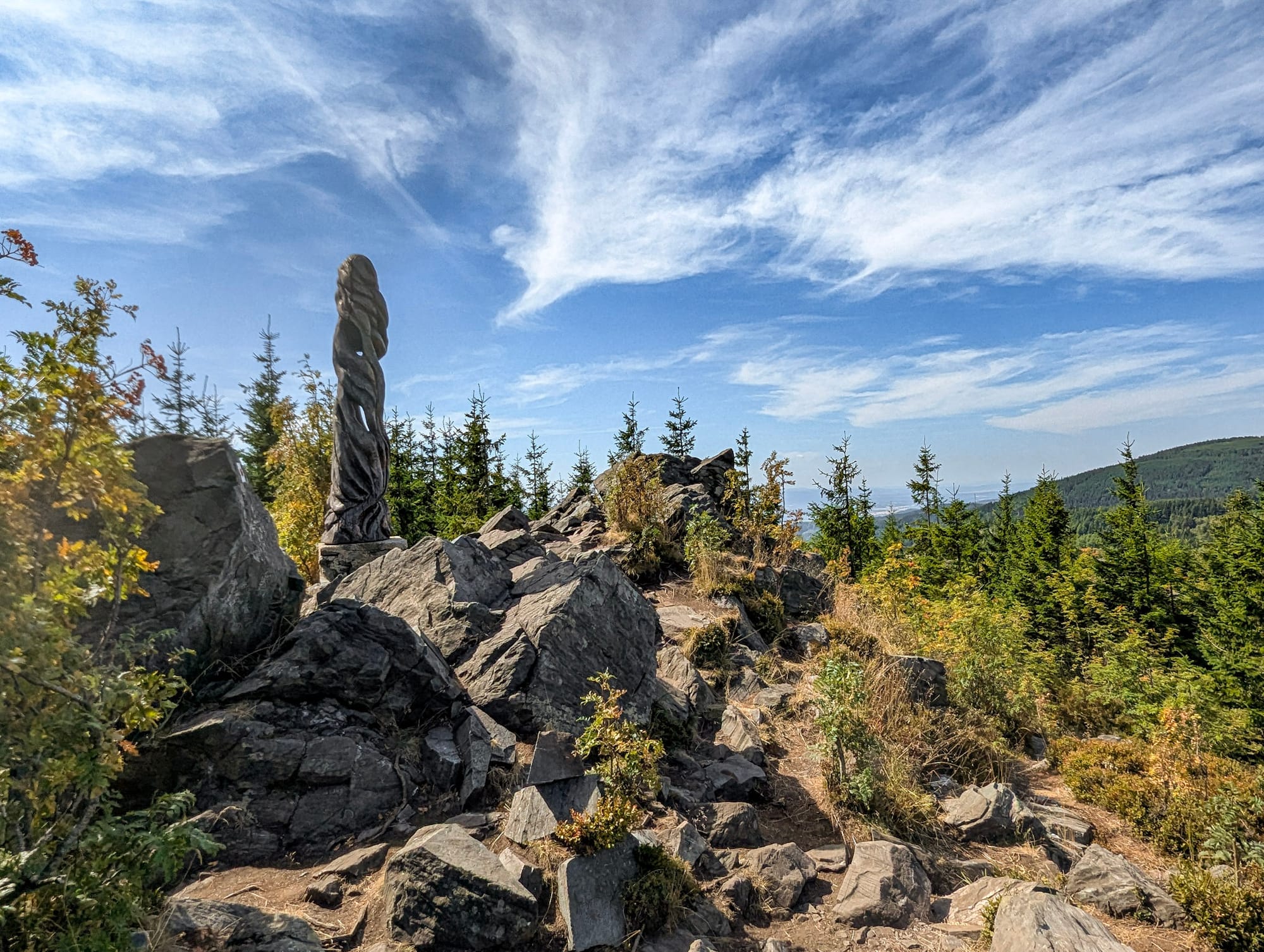 Gipfel des Wirbelsteins mit vielen Gesteinsbrocken und einer Holzskulptur.