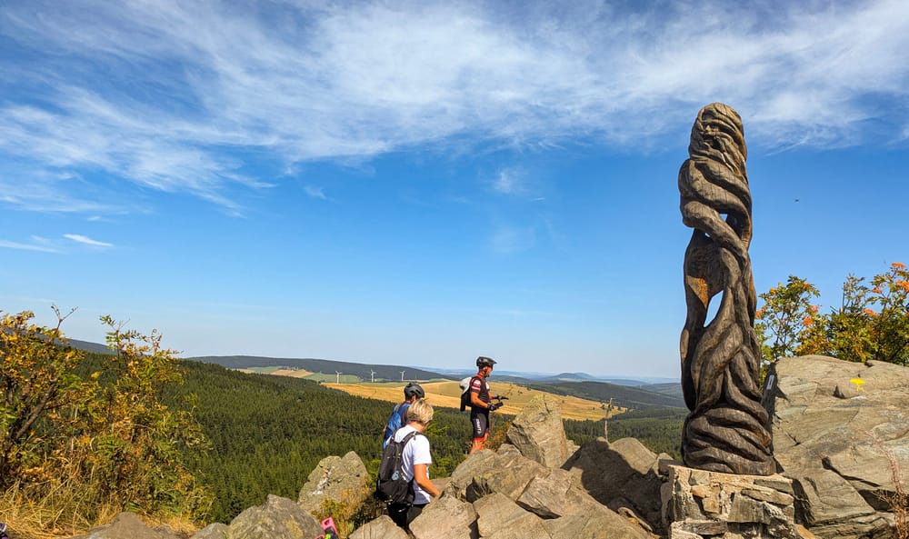 Berggipfel des Wirbelstein im tschechischen Erzgebirge mit Wanderern und Skulptur.